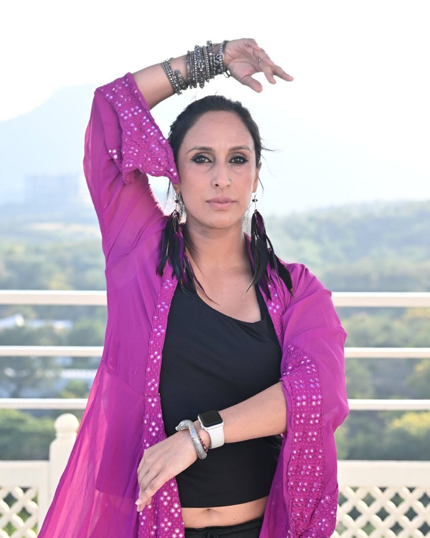 Sejal dancing beneath a carved white arch, wearing magenta